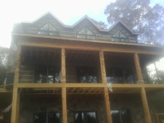 Dormers and porch framing on a large log home under construction — Roof Coating work by our crew in Crystal City