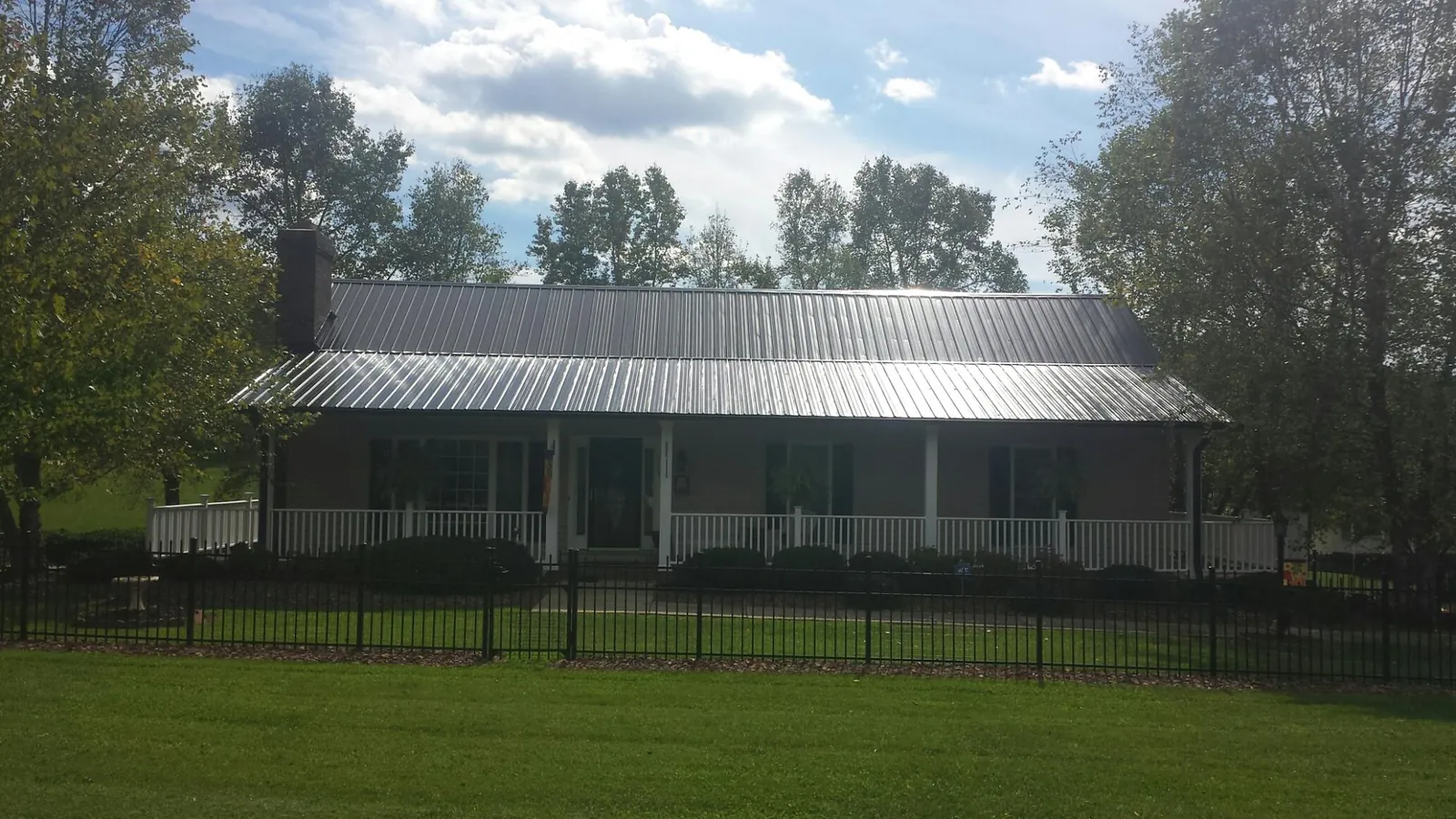 Gray metal roof on a brick ranch with a full width front porch — Gutter Guard Installation work by our crew in Crystal City