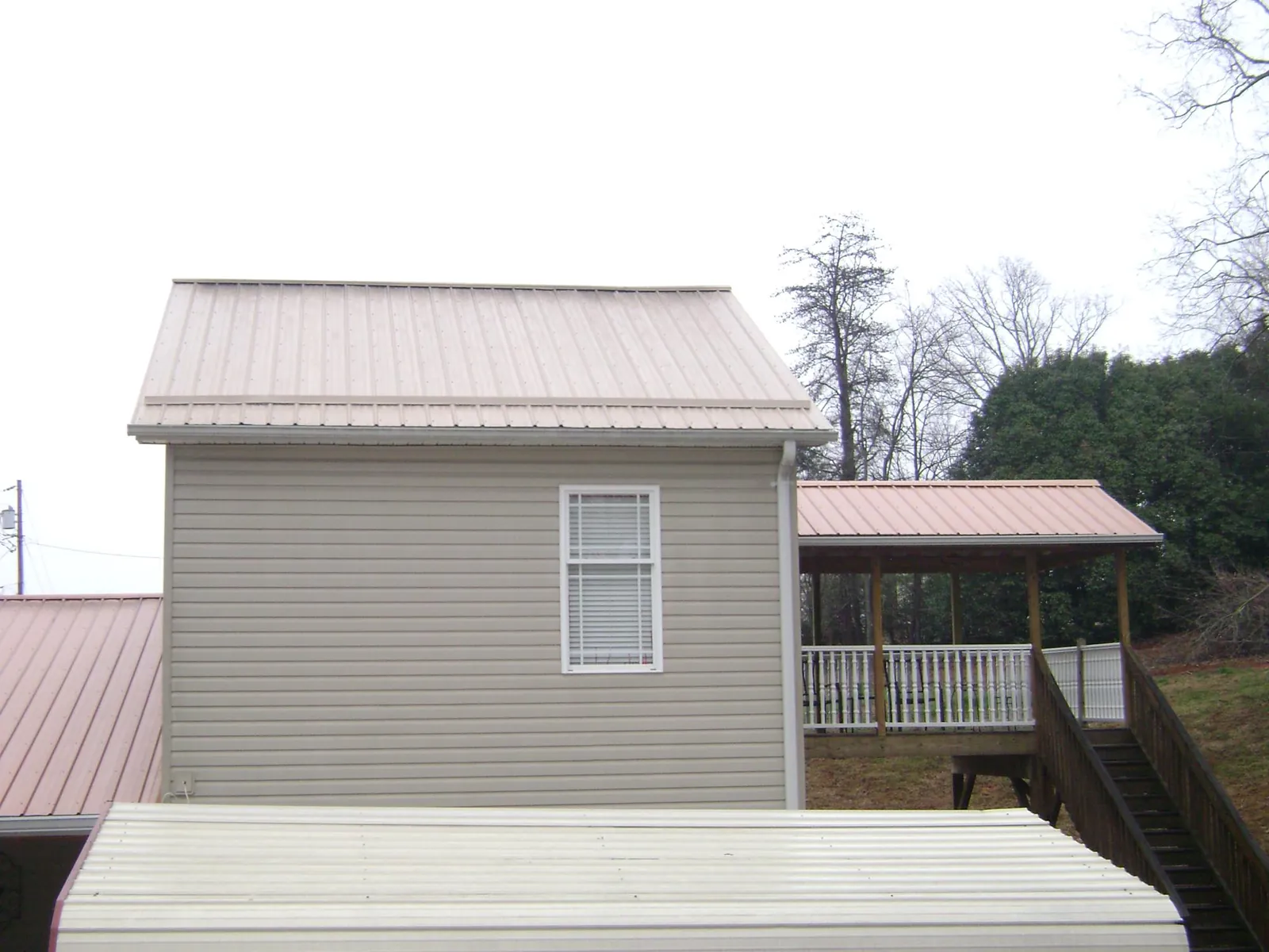 Tan metal roofs on a two story addition and attached porch, from a Roof Replacement job in Crystal City