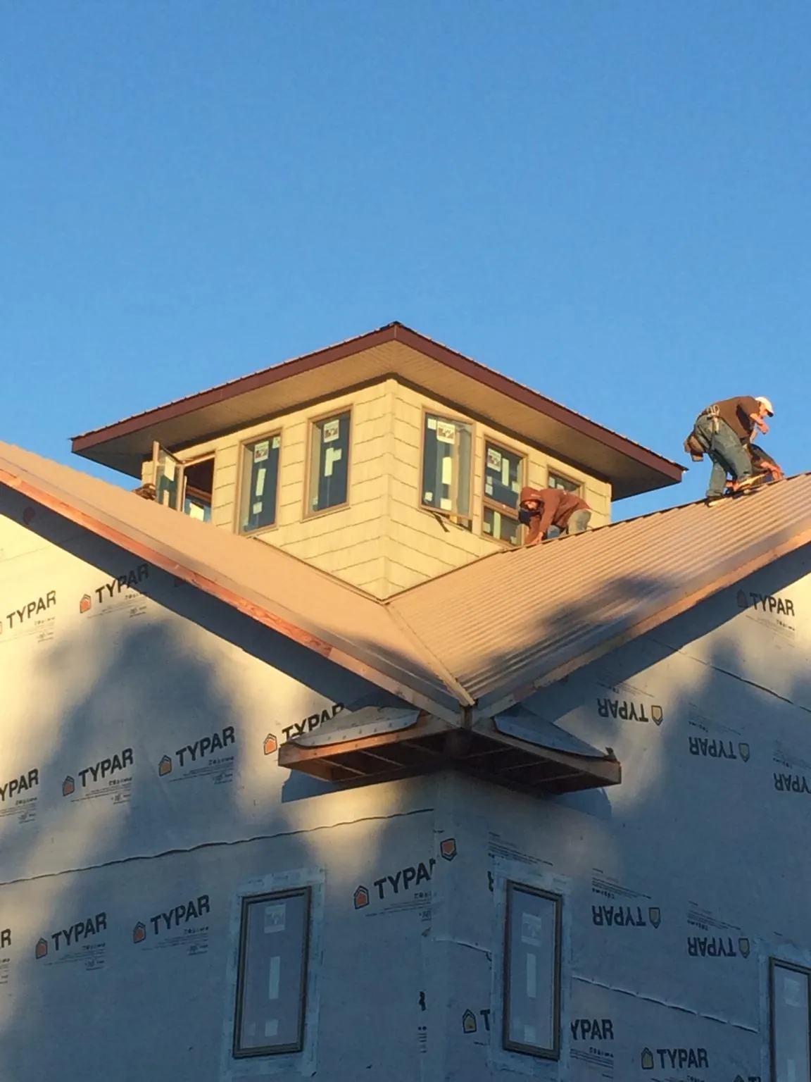 Roofers working around a rooftop cupola on a new metal roof at sunset — Roof Waterproofing in Crystal City by Roofing Brothers